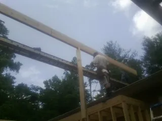 Carpenter setting a ridge beam over a new addition frame — Ice Dam Removal by Roofing Brothers in East Calais