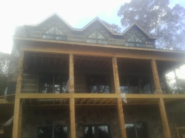 Dormers and porch framing on a large log home under construction — Roof Coating work by our crew in East Calais