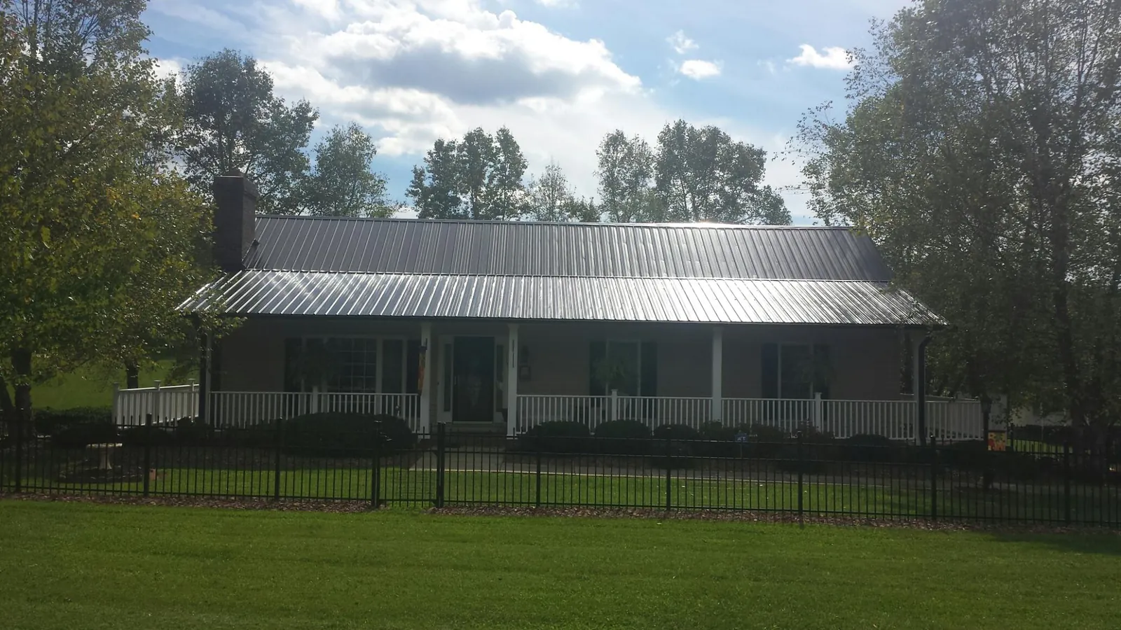 Gray metal roof on a brick ranch with a full width front porch — Gutter Guard Installation work by our crew in East Calais
