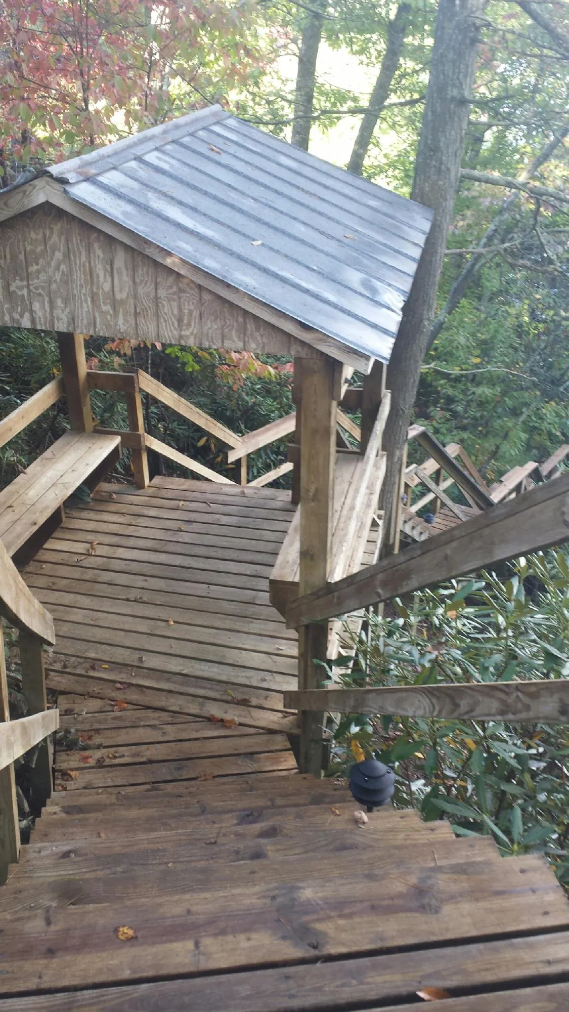 Metal roofed shelter over wooden steps on a wooded walkway — Skylight Repair & Installation work by our crew in East Calais