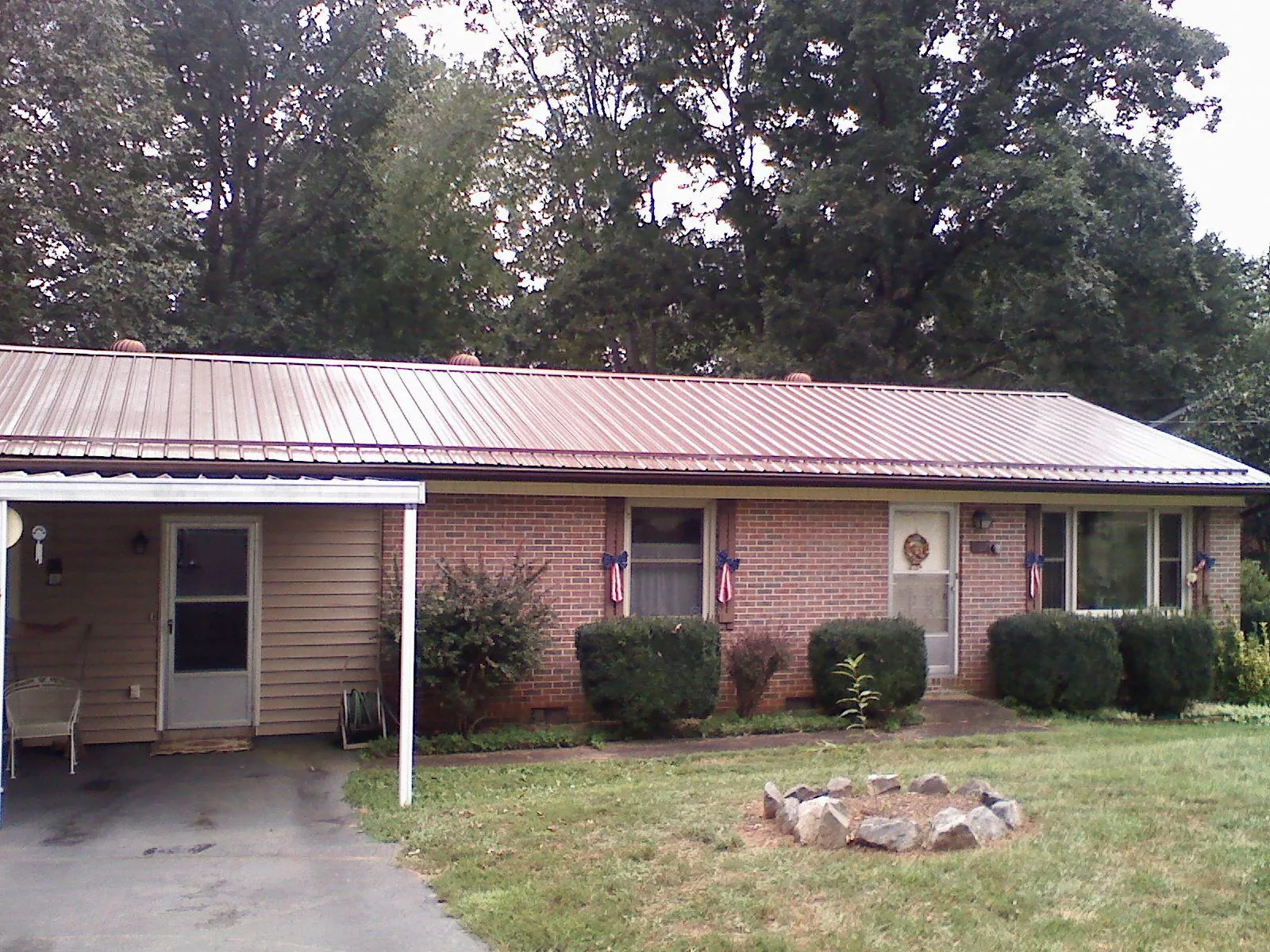 Bronze metal roof and carport on a brick ranch home — Roof Repair work by our crew in East Calais