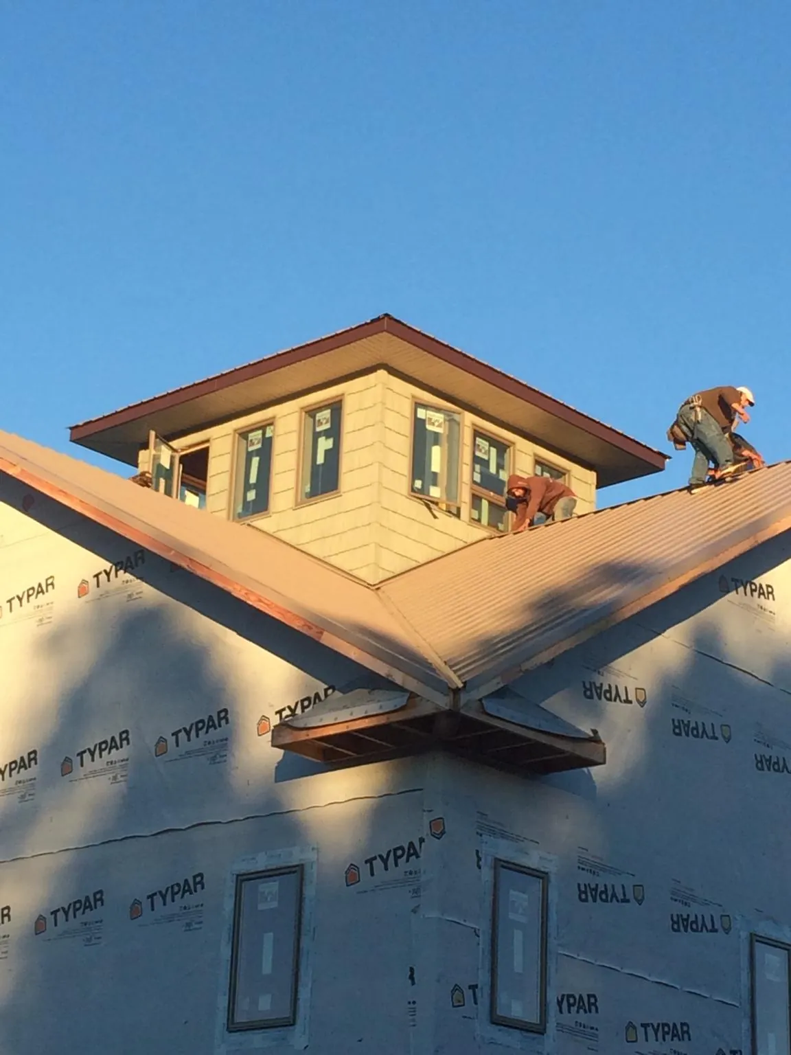 Roofers working around a rooftop cupola on a new metal roof at sunset — Roof Waterproofing in East Calais by Roofing Brothers